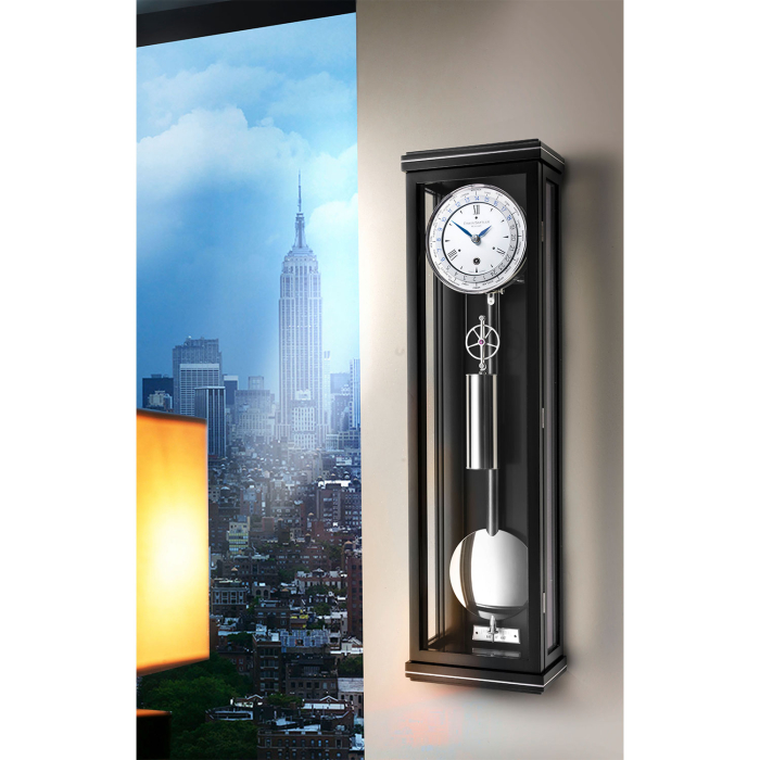 Design-Wanduhr Classica W 60 M mit schwarzem Gehäuse und poliertem Pendel vor Skyline