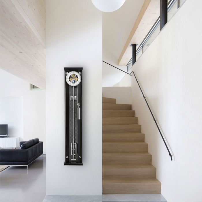 Exklusive Präzisionspendeluhr Opus Secunda M 130 von Erwin Sattler an einer weißen Wand mit Treppenaufgang