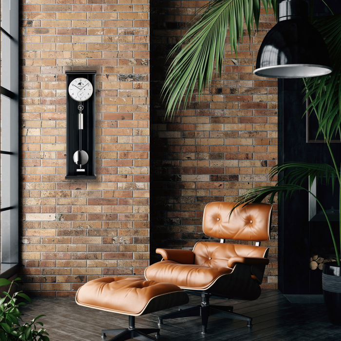 Erwin Sattler Opus PMD 70 im Interior mit Ziegelwand und Design-Loungechair – Präzisionspendeluhr als Wohnakzent