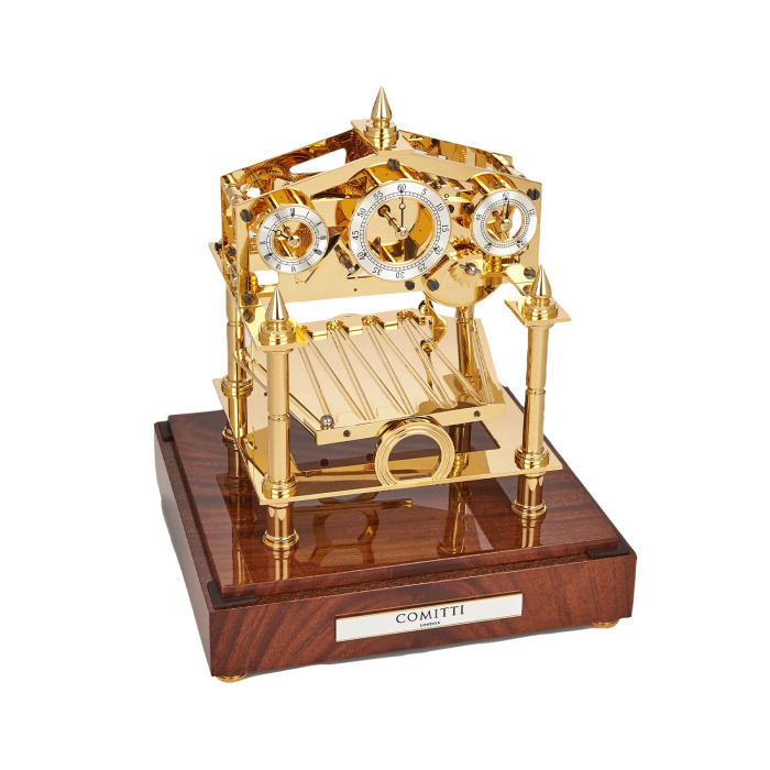 Schrägansicht der Comitti The Congreve Gold Uhr mit glänzendem Mahagonisockel und aufwendig vergoldetem Werk.