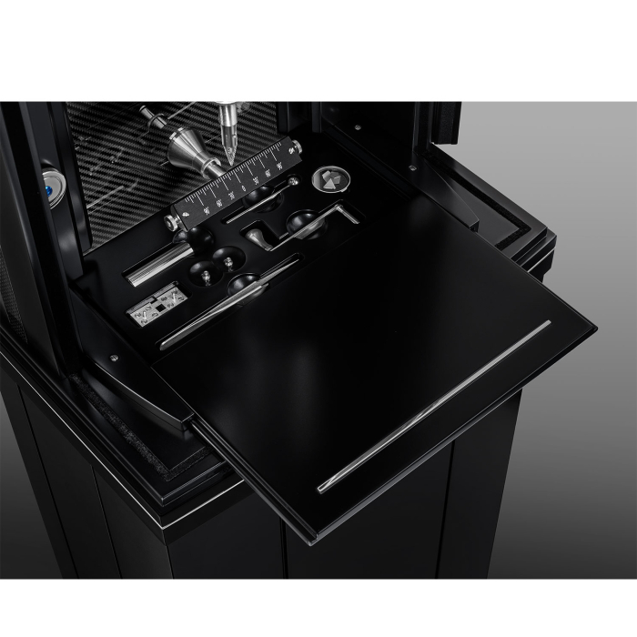 Schublade mit hochwertigem Uhrenwerkzeug und Zubehör im Sockel der Erwin Sattler Illumina Secunda Carbon, mit Carbon-Verkleidung im Hintergrund.