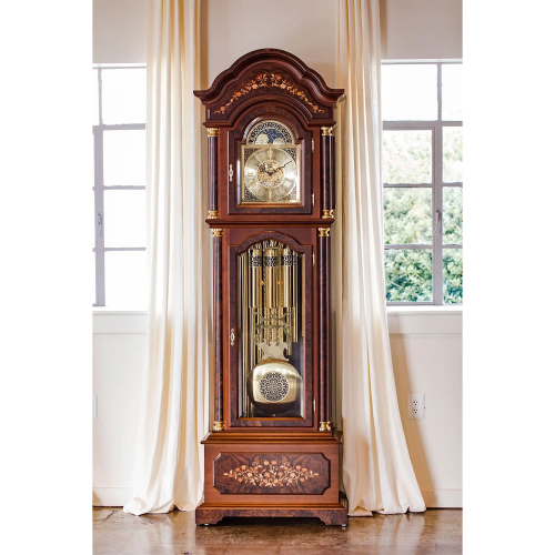 Hermle Standuhr 01210-031171 aus Nussbaum mit Intarsien, goldfarbenem Zifferblatt und Westminster-Pendelwerk, aufgenommen im eleganten Wohnambiente.