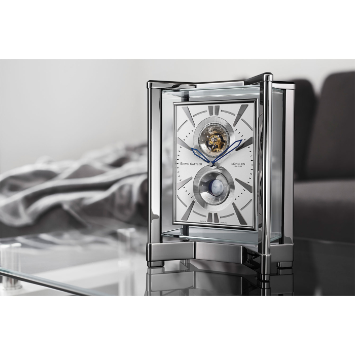 Silberne Erwin Sattler Opus Moon Tourbillon auf Glastisch mit Wohnambiente im Hintergrund